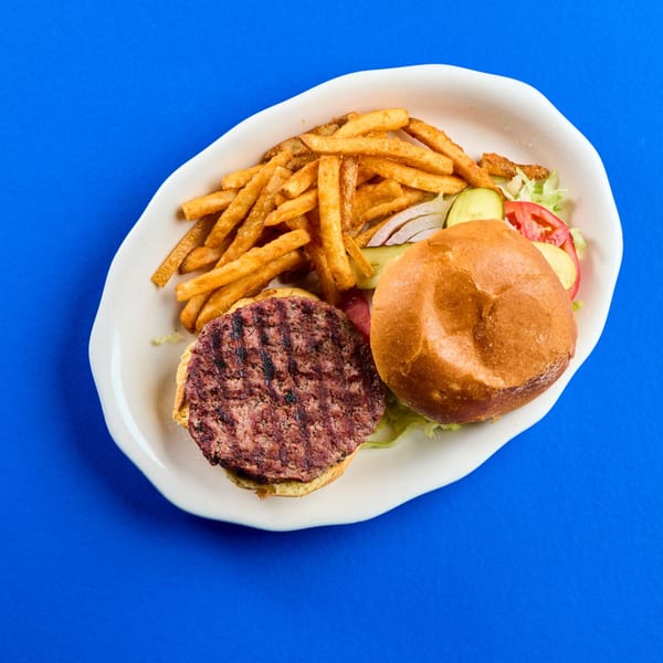 La Bamba's grilled burger patty and bun with fries, lettuce, tomato, onion, and pickles.