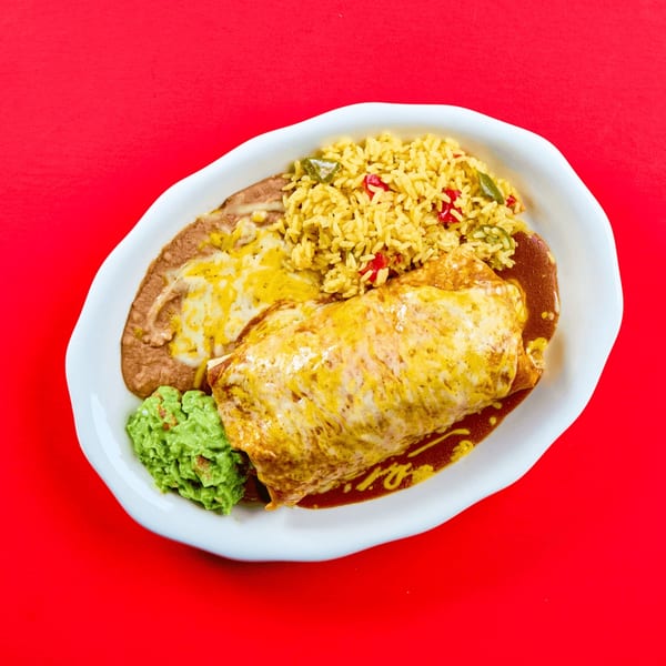 A cheesy burrito with refried beans, yellow rice, and guacamole on a white plate.