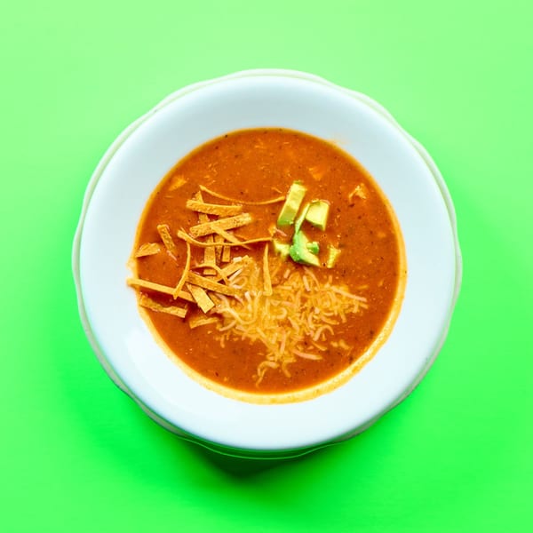 La Bamba's Mexican tortilla soup with avocado, shredded cheese, and tortilla strips in a white bowl.