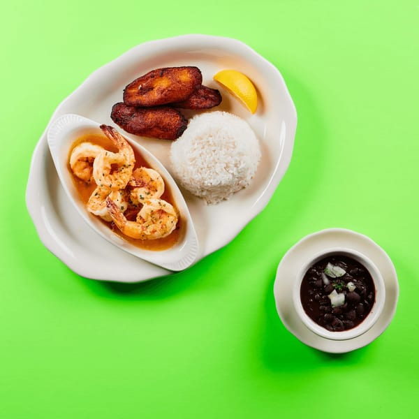 La Bamba's shrimp dish with rice, plantains, and a side of black beans on a green background.
