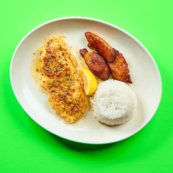 La Bamba's Mexican dish with seasoned chicken, white rice, fried plantains, and a lemon wedge.