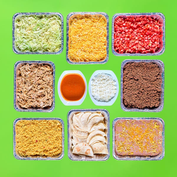 A vibrant spread of La Bamba's Mexican catering, including meats, rice, beans, tortillas, and toppings.