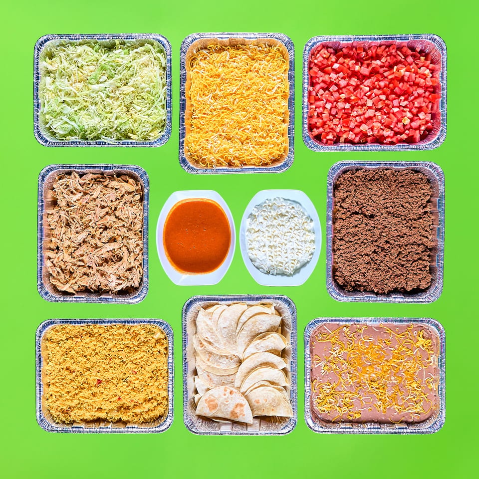 A vibrant spread of La Bamba's Mexican catering, including meats, rice, beans, tortillas, and toppings.